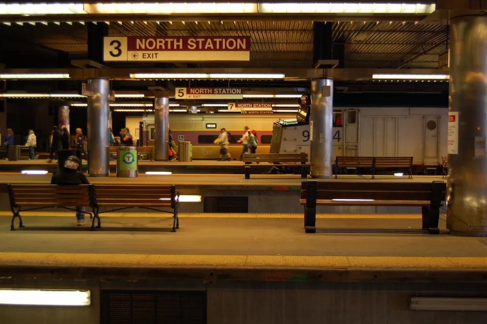 Few passengers waiting in subway station with multiple platforms and "North Station" signs in Boston, Massachusetts